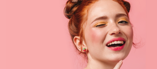 Image of a woman winking wearing strawberry stud earrings