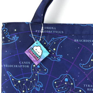 Blue tote bag with dinosaur constellation design and a visible brand tag.