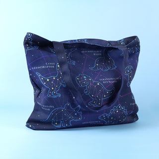 Navy tote bag with dinosaur constellation design on a light blue background